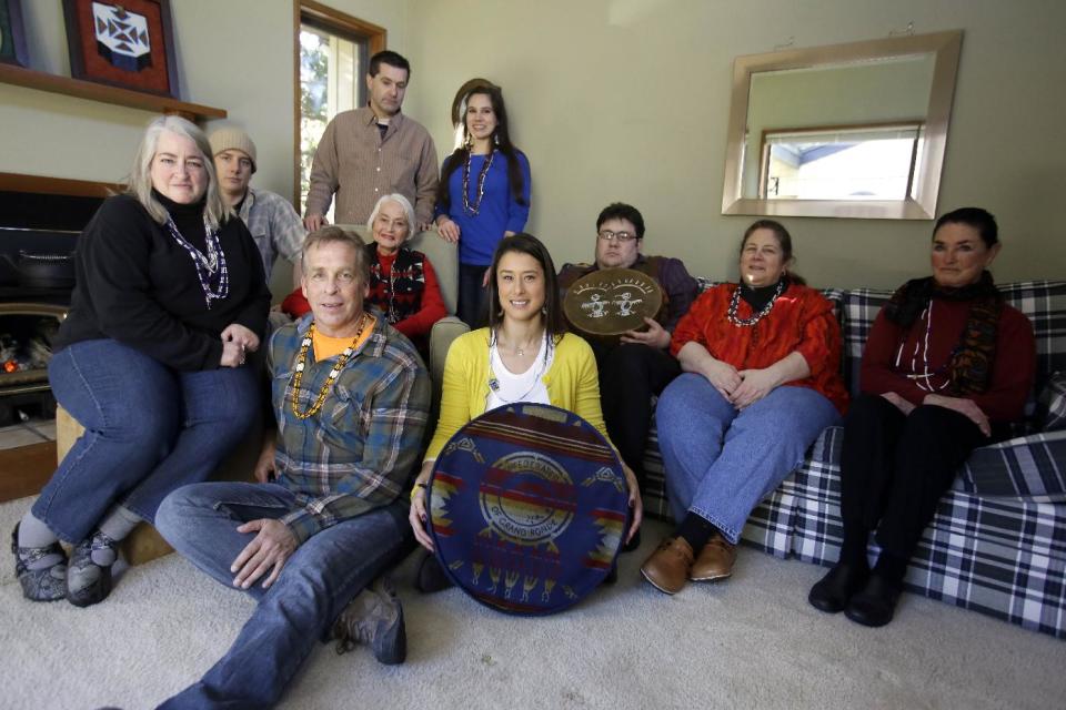 Mia Prickett, seated on the floor holding a Confederated Tribe of Grande Ronde drum, poses for a photo with family members in Portland, Ore., Thursday, Jan. 16, 2014. Prickett’s ancestor Tumulth, a leader of the Cascade Indians along the Columbia River, was one of the chiefs who signed an 1855 treaty that helped establish the Confederated Tribes of the Grand Ronde in Oregon. But the Grand Ronde now wants to disenroll Prickett and 79 relatives because they no longer satisfy new enrollment requirements. Also seated on floor is Russell Wilkinson. Seated second row from left are Nina Portwood-Shields, Jade Unger, Marilyn Portwood, Eric Bernando, Debi Anderson, Val Alexander. Standing are Antoine Auger, left an Erin Bernando.(AP Photo/Don Ryan)