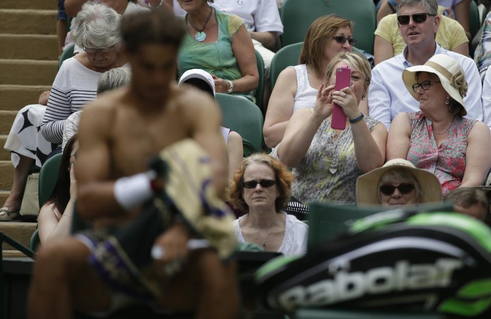 RNPS YEAR END 2014 - BEST OF SPORT ODDLY Spectators take photographs of Rafael Nadal of Spain as he changes his shirt during his men's singles tennis match against Lukas Rosol of the Czech Republic at the Wimbledon Tennis Championships, in London, in this June 26, 2014 file photo. REUTERS/Max Rossi/Files (BRITAIN - Tags: SPORT TENNIS TPX IMAGES OF THE DAY)