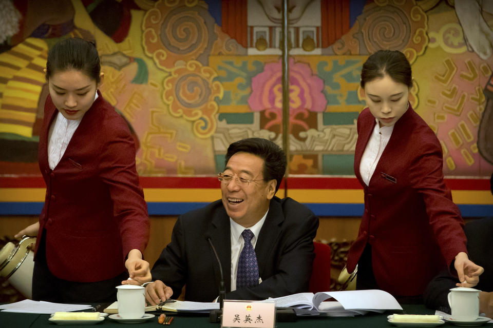 Wu Yingjie, center, Communist Party secretary of the Tibetan Autonomous Region, laughs as attendants refill mugs of tea during a group discussion session held on the sidelines of the annual meeting of China's National People's Congress (NPC) in the Tibet Hall of the Great Hall of the People in Beijing, Wednesday, March 6, 2019. The Chinese Communist Party chief for Tibet said on Wednesday that the Dalai Lama has not done a "single good thing" for the region. (AP Photo/Mark Schiefelbein)