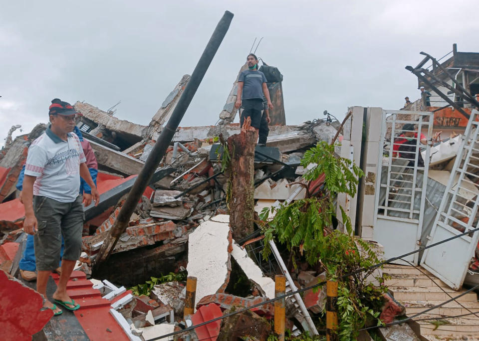 Residents inspect earthquake-damaged houses in Mamuju, West Sulawesi, Indonesia, Friday, Jan. 15, 2021. A strong inland and shallow earthquake hit eastern Indonesia early Friday causing people to panic in parts of the country's Sulawesi island and run to higher ground. (AP Photo/Rudy Akdyaksyah)