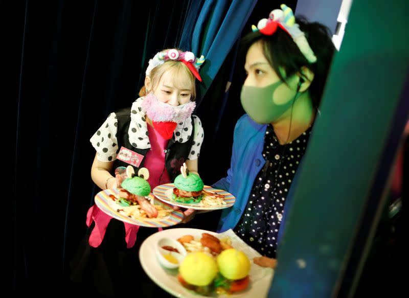 Staff members wearing protective face masks serve foods to guests at Kawaii Monster Cafe amid the coronavirus disease (COVID-19) outbreak, in Tokyo