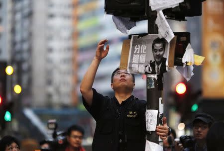 A police official takes down a paper sign after some barricades were removed at a protest site at the commercial area of Causeway Bay in Hong Kong October 14, 2014. REUTERS/Carlos Barria