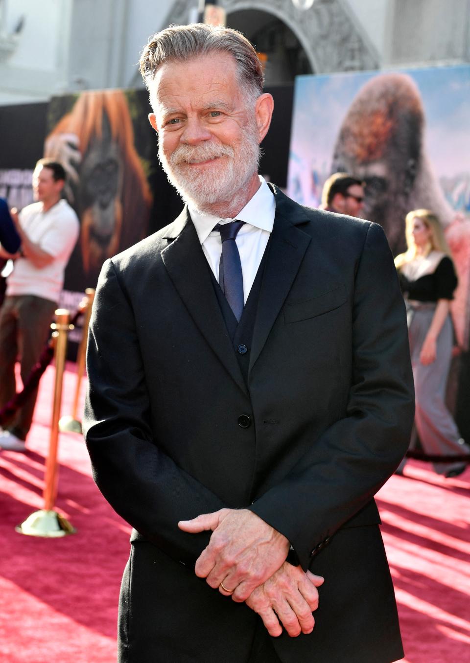 William H. Macy at a film premiere for Kingdom of the Planet of the Apes, wearing a dark suit and tie, with a slight smile