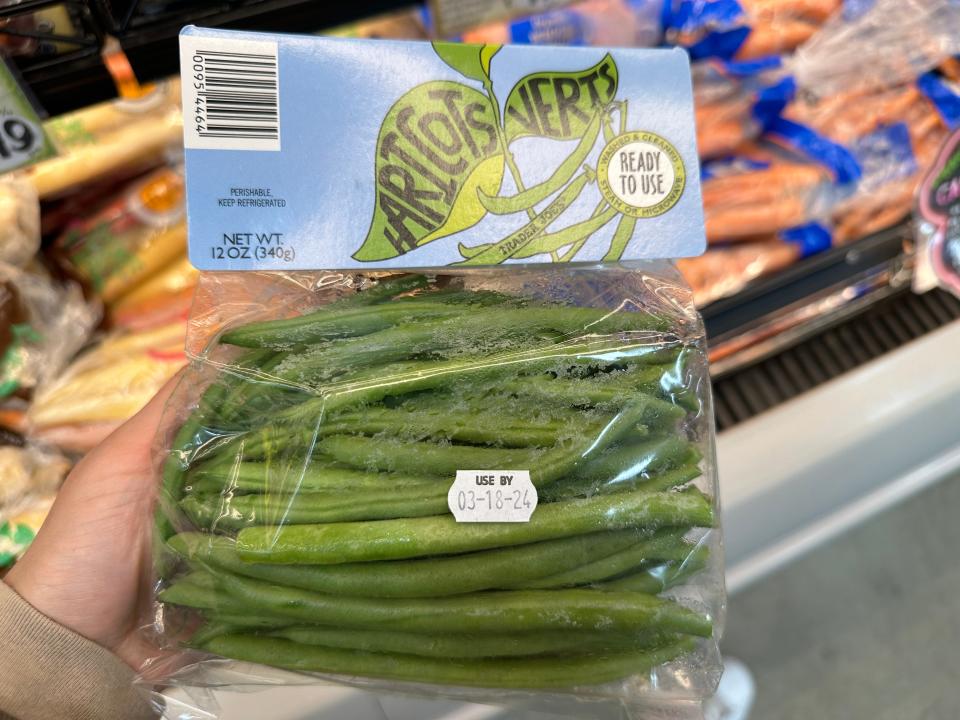 hand holding up a bag of trader joe's fresh green beans