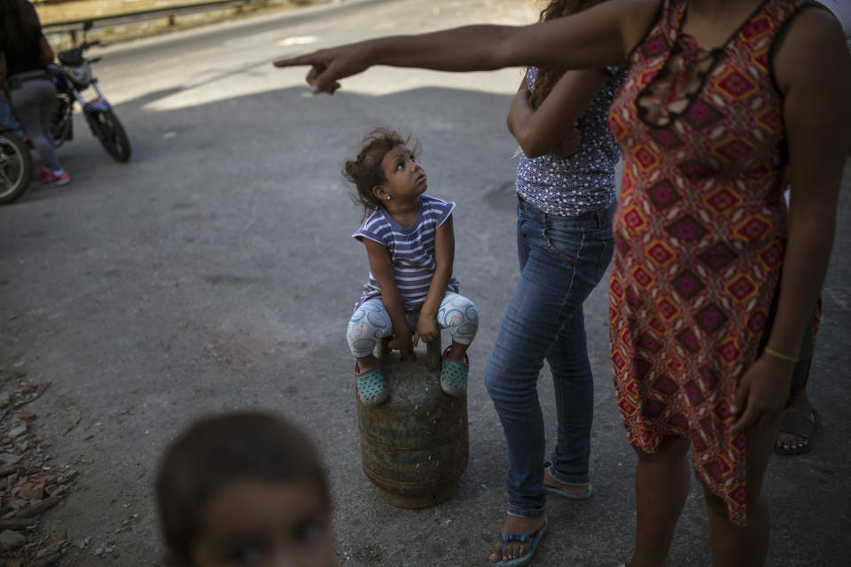 A girl sitting on a full gas container waits for her family to gather before they walk home after buying cooking gas in the Petare slum of Caracas, Venezuela, Sunday, Feb. 10, 2019. Residents pay 3 U.S. cents for each container of natural gas, which is subsidized by the government. (AP Photo/Rodrigo Abd)