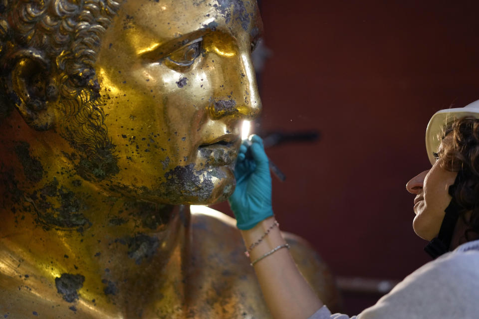 Vatican Museum restorer Alice Baltera works on the bronze Hercules statue, in the Round Hall of the Vatican Museums, Thursday, May 11, 2023. Work will continue until December to reveal the 4-meter- (13-foot-) tall Hercules, believed to have stood in ancient Rome’s Pompey Theater, to its original golden sheen. The discovery of the gilded bronze in 1864 during work on a banker’s villa near Piazza dei Fiori made global headlines. (AP Photo/Andrew Medichini)