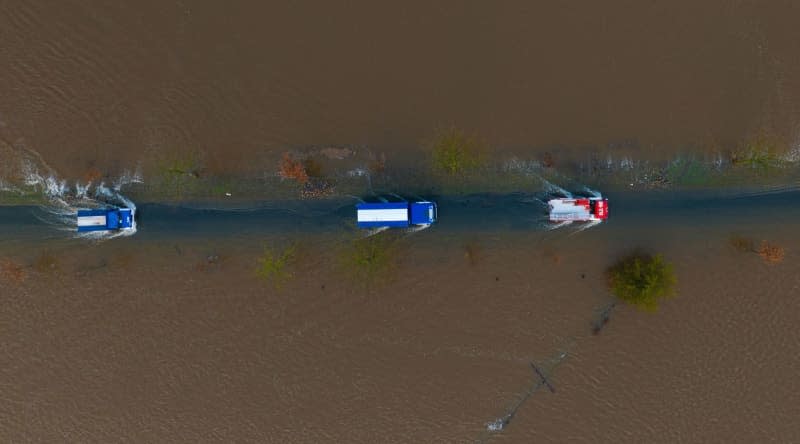 An aerial view of vehicles from the THW and the fire department drive on a partially flooded road not far from the Aller. Philipp Schulze/dpa