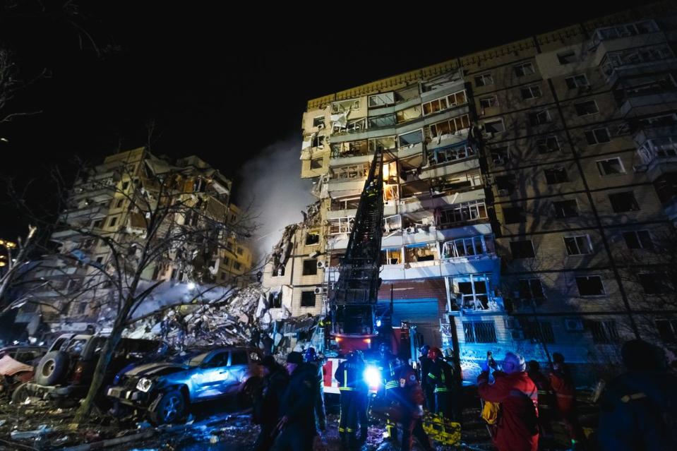 A rescuer climbs a ladder of a fire engine to one of the damaged apartments after a missile strike on Jan. 14, 2023, in Dnipro. Russia's Х-22 cruise missiles fired from a TU-22M3 strategic bomber hit a nine-story residential building in Dnipro, completely destroying one of the sections from top to bottom floors. (Yurii Stefanyak/Global Images Ukraine via Getty Images)