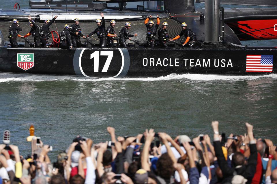 Members of Oracle Team USA wave to spectators after winning Race 18 of the 34th America's Cup yacht sailing race against Emirates Team New Zealand in San Francisco, California September 24, 2013. REUTERS/Stephen Lam (UNITED STATES - Tags: SPORT YACHTING)