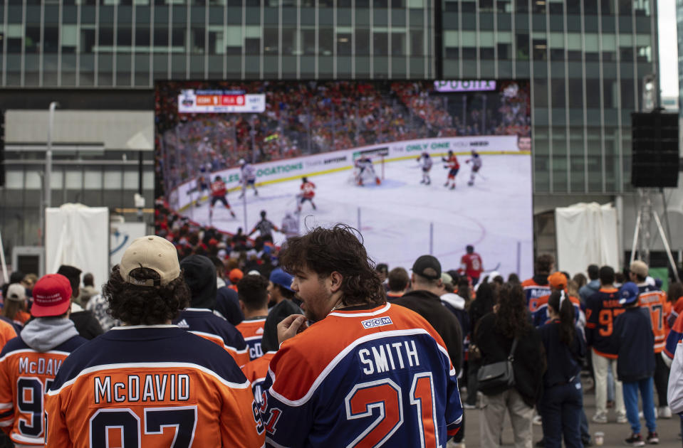 Edmonton Oilers fans watch coverage of Game 5 of the NHL hockey Stanley Cup Final between the Oilers and the Florida Panthers on a large screen Tuesday, June 18, 2024, in Edmonton, Alberta. (Jason Franson/The Canadian Press via AP)