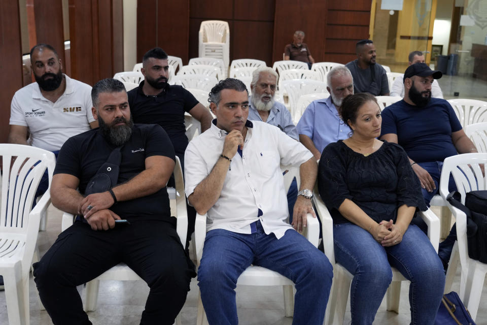 Survivors and relatives of the victims' of a migrant boat sinking off the coast of Tripoli, listen to a news conference where their lawyer announced a lawsuit against the Lebanese military for holding two missing survivors, in Tripoli, northern Lebanon, Thursday, Sept. 1, 2022. In late April, a boat carrying about 80 Lebanese, Syrians, and Palestinians trying to migrate by sea to Italy sunk following a confrontation with the Lebanese navy. (AP Photo/Bilal Hussein)