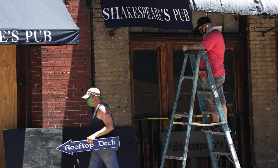 Workers who only gave their first names, Joe, left, and Danny, right, work to prepare their pub that they hope to reopen soon in Austin, Texas, Monday, May 18, 2020. Texas continues to go through phases as the state reopens after closing many non-essential businesses to help battle the spread of COVID-19. (AP Photo/Eric Gay)