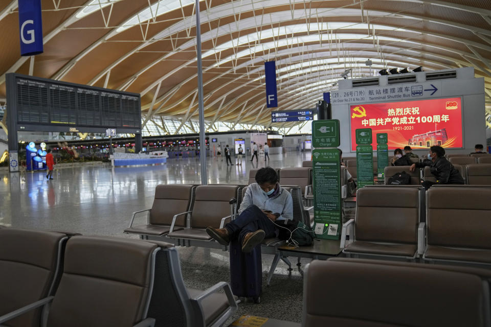 Passengers take rest near a blank flights information board at Pudong International Airport in Shanghai, China, Sunday, July 25, 2021. Airline flights were canceled in eastern China and cargo ships were ordered out of the area Saturday as Typhoon In-fa churned toward the mainland after dumping rain on Taiwan. (AP Photo/Andy Wong)