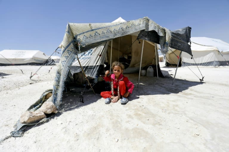 A Syrian girl, who fled the countryside surrounding the Islamic State group's Syrian stronghold of Raqa, sits in the shade of a tent at a temporary camp in the village of Ain Issa on July 11, 2017