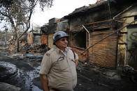 A fire fighting officer stands at the Gokul Puri tyre market which was burnt in Tuesday's violence in New Delhi, India, Wednesday, Feb. 26, 2020. At least 20 people were killed in three days of clashes in New Delhi, with the death toll expected to rise as hospitals were overflowed with dozens of injured people, authorities said Wednesday. The clashes between Hindu mobs and Muslims protesting a contentious new citizenship law that fast-tracks naturalization for foreign-born religious minorities of all major faiths in South Asia except Islam escalated Tuesday. (AP Photo/Altaf Qadri)