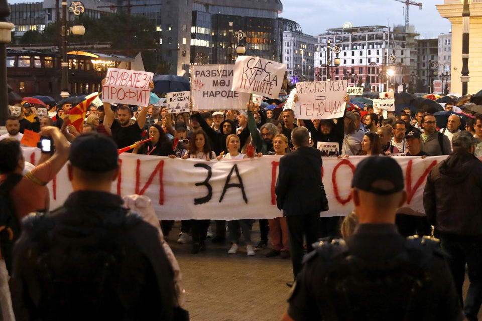 Protestors carry banners near a police cordon in front of the public prosecution building in Skopje, North Macedonia, on Monday, Sept. 4. 2023. Thousands have gathered late on Monday in front of the government in North Macedonia's capital Skopje to protest on scandal that broke after media reported that employees in the state running Clinic of Oncology allegedly were selling on a black market a million of dollars' worth clinic supply of drugs needed for cancer treatment. (AP Photo/Boris Grdanoski)