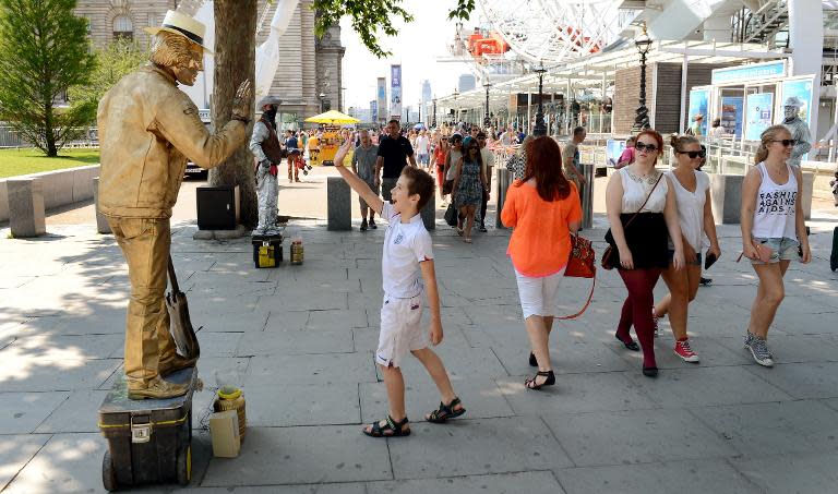 A busker is seen entertaining tourists in front of the London Eye, on July 25, 2012