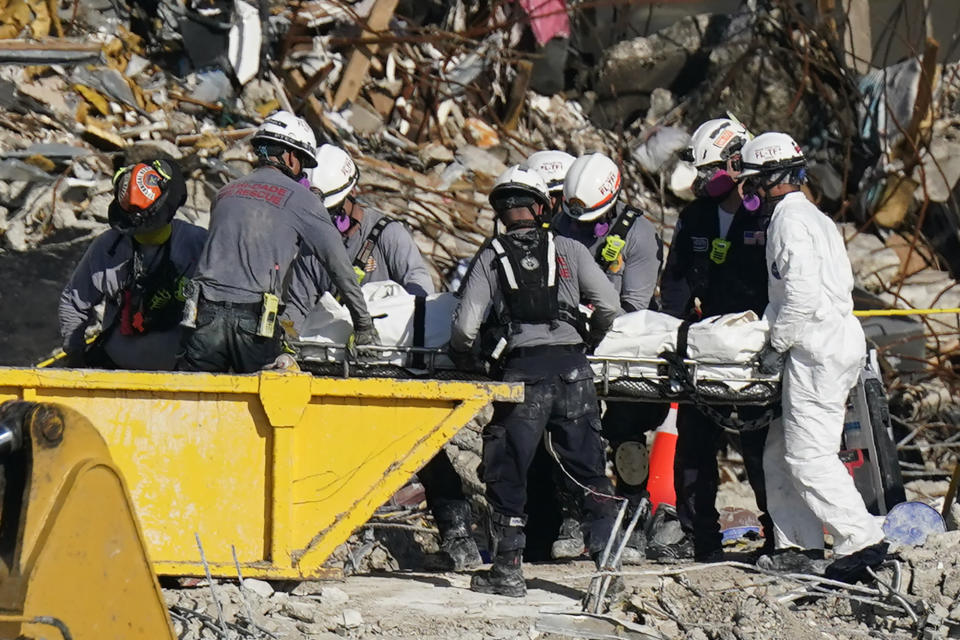 Search and rescue personnel remove remains on a stretcher as they work atop the rubble at the Champlain Towers South condo building where scores of people remain missing more than a week after it partially collapsed, Friday, July 2, 2021, in Surfside, Fla. Rescue efforts resumed Thursday evening after being halted for most of the day over concerns about the stability of the remaining structure.(AP Photo/Mark Humphrey)