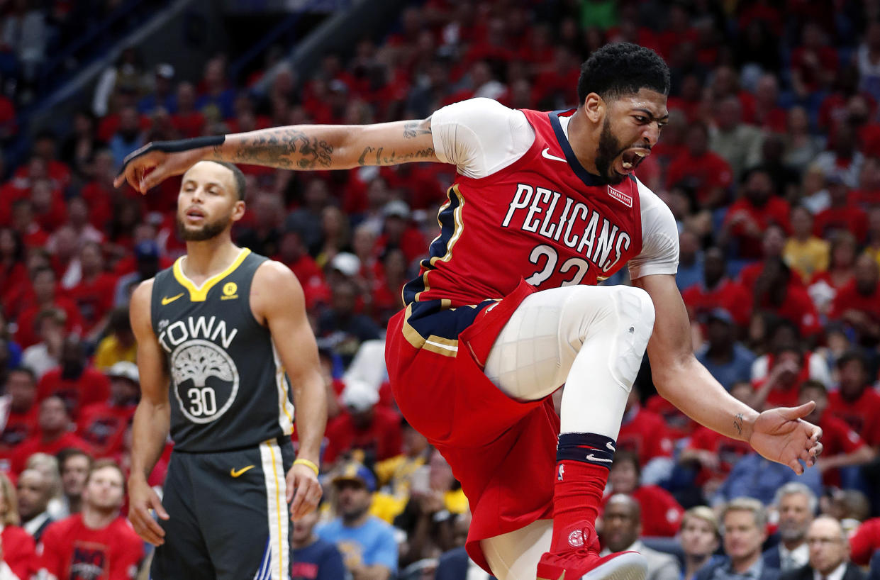 Anthony Davis roars after a monster slam dunk during Friday’s Game 3, and Stephen Curry can’t do much about it. (AP)