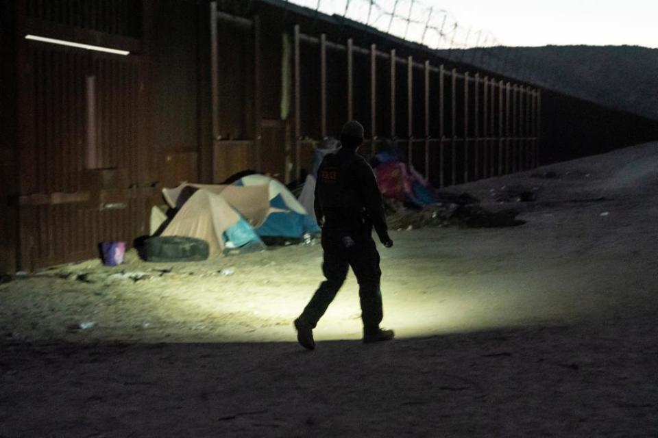 A border patrol agent checks on tents by the border wall in Jacumba Hot Springs, California, on 11 November 2023.