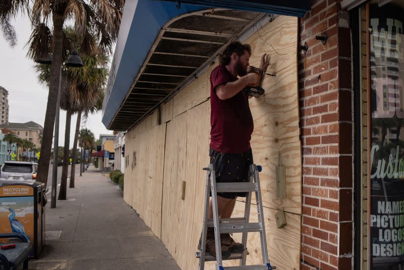 Steve Pizzano ayuda a tapiar la tienda de recuerdos de un amigo ante la llegada del huracán Idalia en Clearwater Beach, Florida, Estados Unidos
