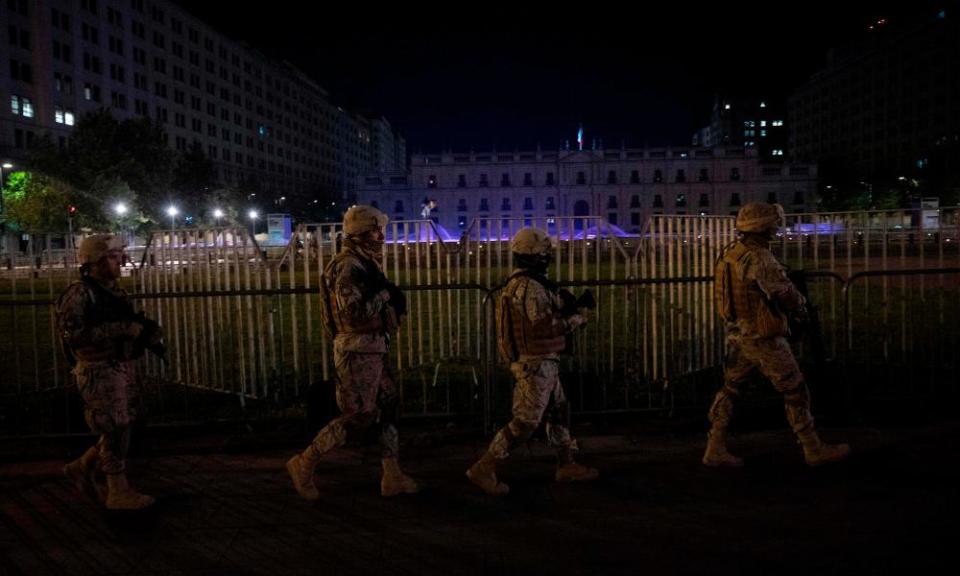 Soldiers patrol the presidential government palace during curfew in Santiago on Monday night.