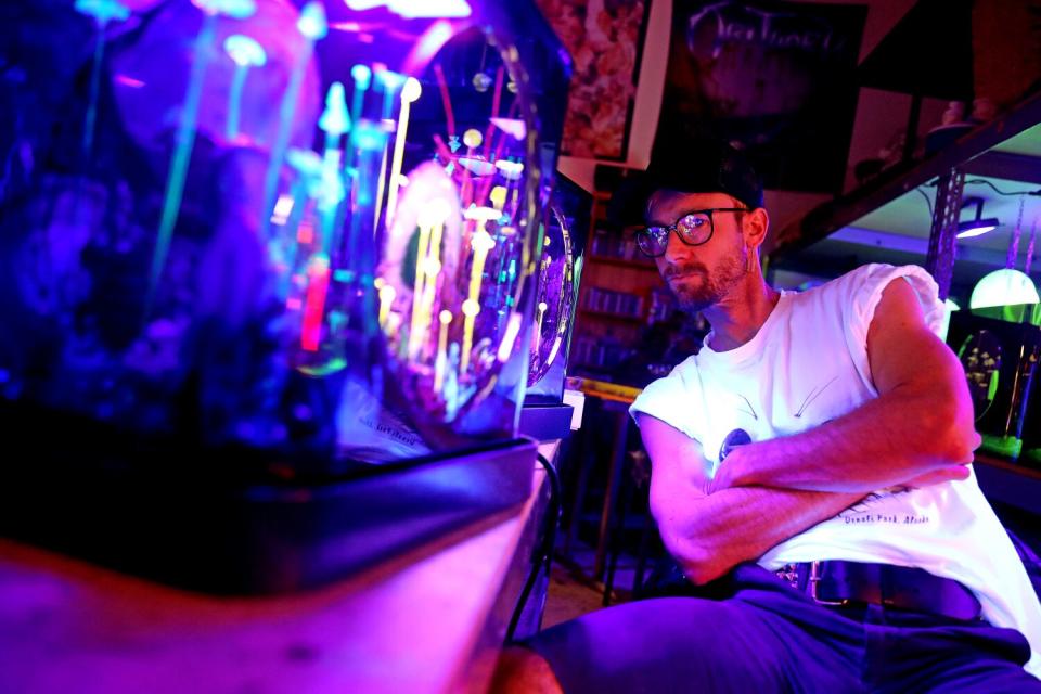 Max Hooper Schneider, in a baseball cap and glasses, at his studio