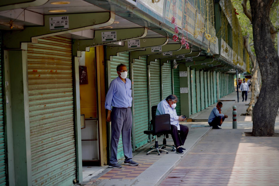 A man wearing a mask stands outside one of the shops which opened at the Janpath market in New Delhi, India, Monday, June 1, 2020. More states opened up and crowds of commuters trickled onto the roads in many of India's cities on Monday as a three-phase plan to lift the nationwide coronavirus lockdown started despite an upward trend in new infections. (AP Photo/Manish Swarup)