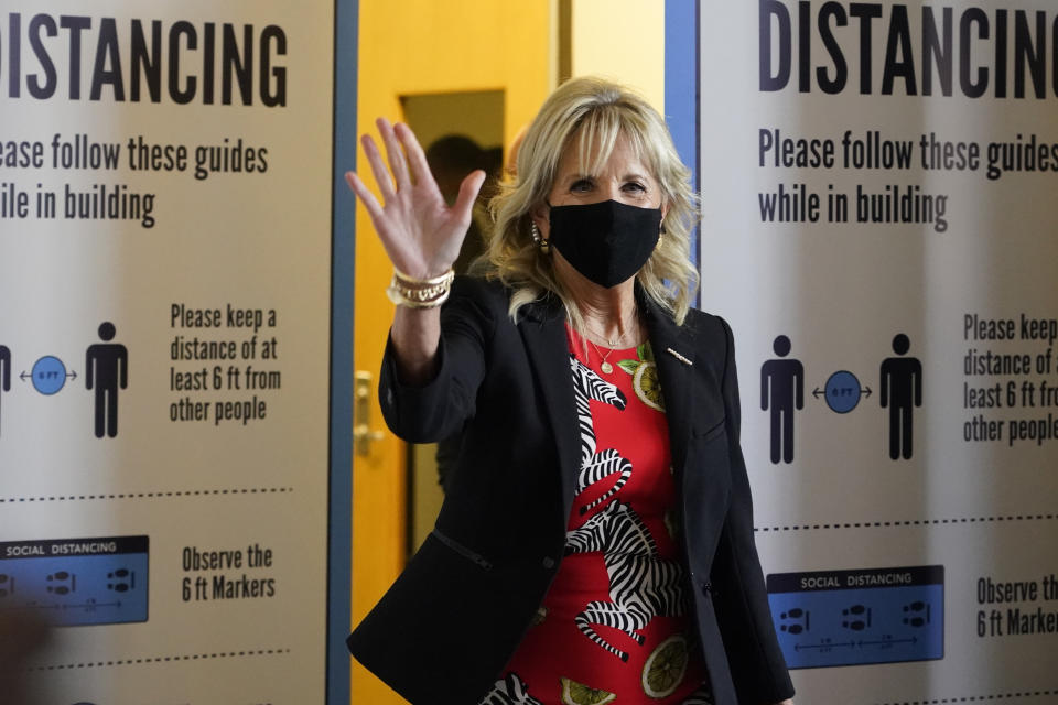 First lady Jill Biden waves to assembled local media as she makes her way past COVID education posters during a visit to vaccination site at Jackson State University in Jackson, Miss., Tuesday, June 22, 2021, as part of the Biden administration's nationwide tour to reach Americans who haven't been vaccinated and to promote vaccine education. (AP Photo/Rogelio V. Solis)