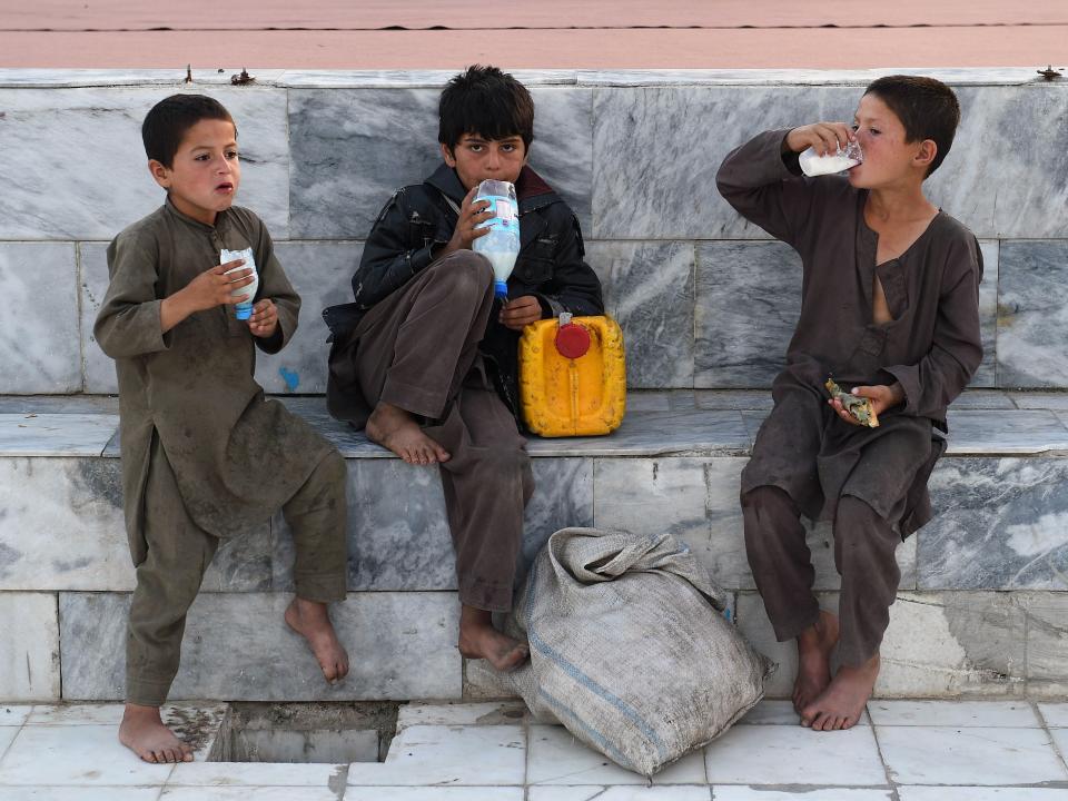 In this photograph taken on May 14, 2019, Afghan boys enjoy yogurt-based drinks in the courtyard of the Hazrat-e Ali shrine, or 'Blue Mosque', during the holy month of Ramadan in Mazar-i-Sharif.