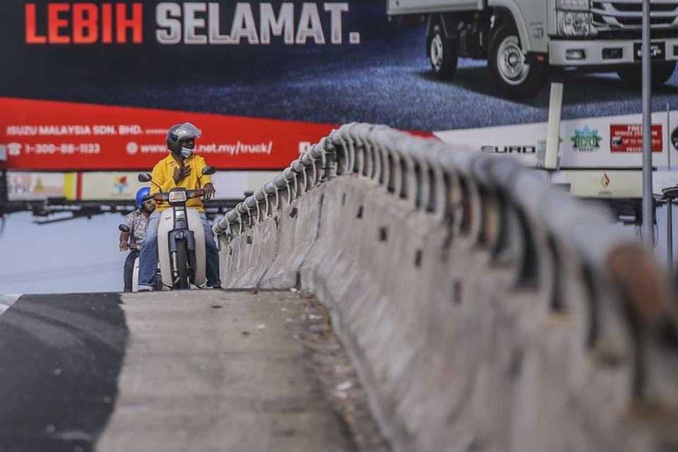 Motorcyclists stop for a quick prayer by the side of a flyover overlooking Batu Caves during Thaipusam January 28, 2021. — Picture by Hari Anggara