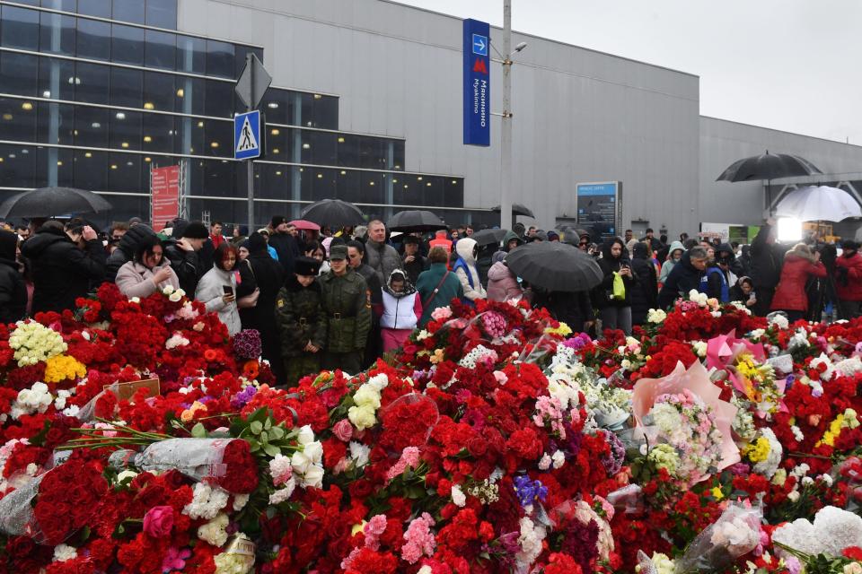 People lay flowers at a makeshift memorial in front of the Crocus City Hall in Krasnogorsk as Russia observes a national day of mourning after a massacre that killed more than 130 people.