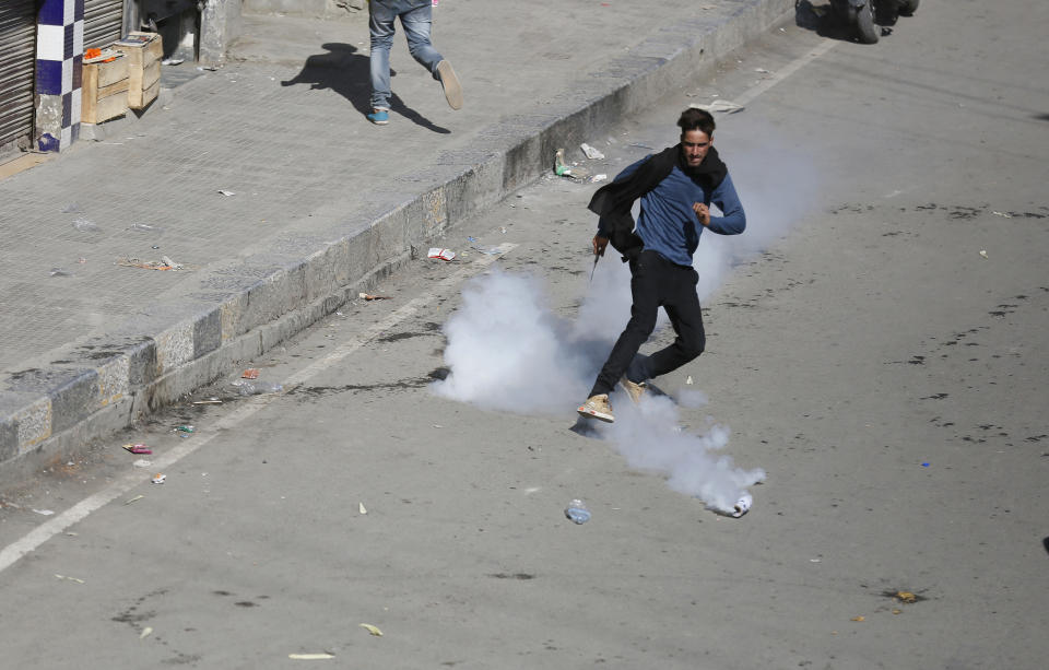 A Kashmiri Shiite Muslim kicks an exploded tear gas shell at Indian policemen as they clash during a Muharram procession in Srinagar, Indian controlled Kashmir, Wednesday, Sept. 19, 2018. Police and paramilitary soldiers on Wednesday used batons and fired tear gas to disperse hundreds of Muslims participating in religious processions in the Indian portion of Kashmir. Authorities had imposed restrictions in parts of Srinagar, the region's main city, to prevent gatherings marking Muharram from developing into anti-India protests. (AP Photo/Mukhtar Khan)