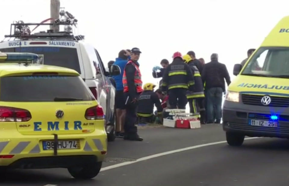 In this image from video, emergency services attend to injured at the scene after a tour bus crashed at Canico, on Portugal's Madeira Island, Wednesday April 17, 2019. Some 28 people are reported to have died in the crash, most of them German tourists, local mayor Filipe Sousa told TV news. (TVI via AP)