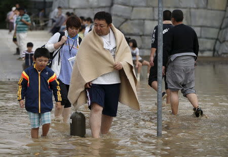 Local residents wade through a residential area flooded by the Kinugawa river, caused by typhoon Etau, in Joso, Ibaraki prefecture, Japan, September 11, 2015. REUTERS/Issei Kato