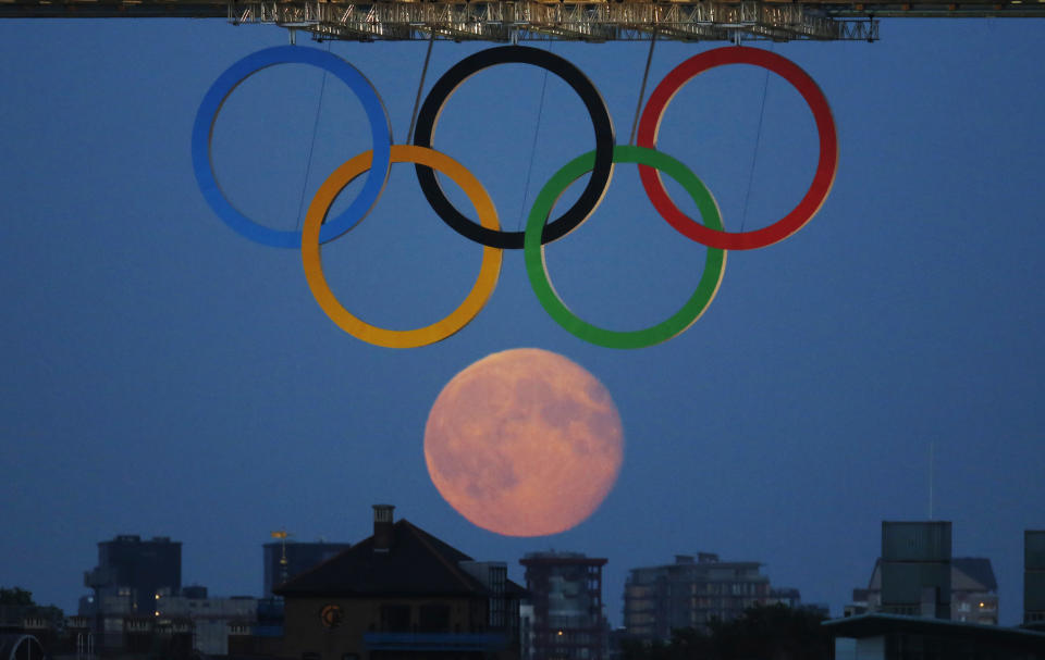 The full moon rises through the Olympic Rings hanging beneath Tower Bridge during the London 2012 Olympic Games August 3, 2012. REUTERS/Luke MacGregor (BRITAIN - Tags: SPORT OLYMPICS ENVIRONMENT CITYSPACE)