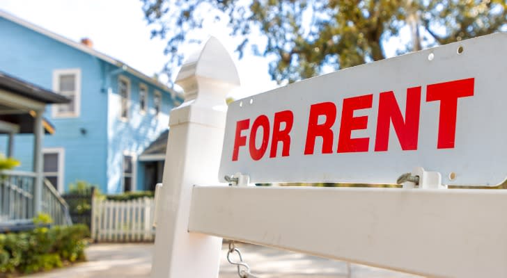 A "For Rent" signs hangs in front of a rental property.