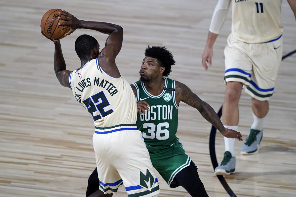 Milwaukee Bucks' Khris Middleton (22) looks to pass around Boston Celtics' Marcus Smart (36) during the first half of an NBA basketball game Friday, July 31, 2020, in Lake Buena Vista, Fla. (AP Photo/Ashley Landis, Pool)