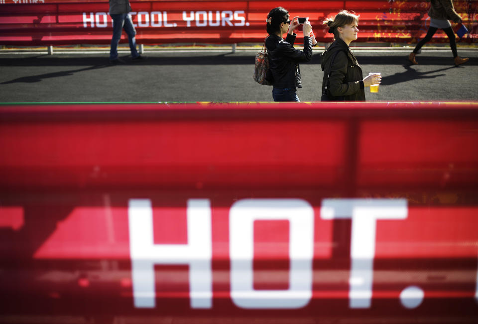 In this Wednesday, Feb. 12, 2014, photo, visitors enter the Olympic Park at the 2014 Winter Olympics, in Sochi, Russia. Temperatures were near 60 degrees Fahrenheit in Sochi on Wednesday. (AP Photo/David Goldman)