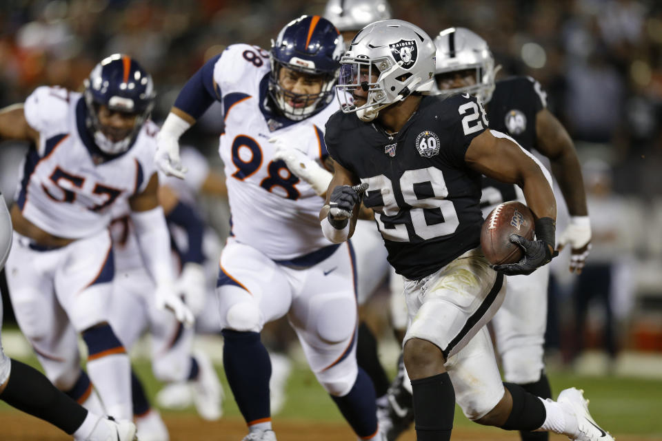 Oakland Raiders running back Josh Jacobs runs with the ball as Denver Broncos defensive end DeMarcus Walker (57) and nose tackle Mike Purcell (98) look on during the first half of an NFL football game Monday, Sept. 9, 2019, in Oakland, Calif. (AP Photo/D. Ross Cameron)