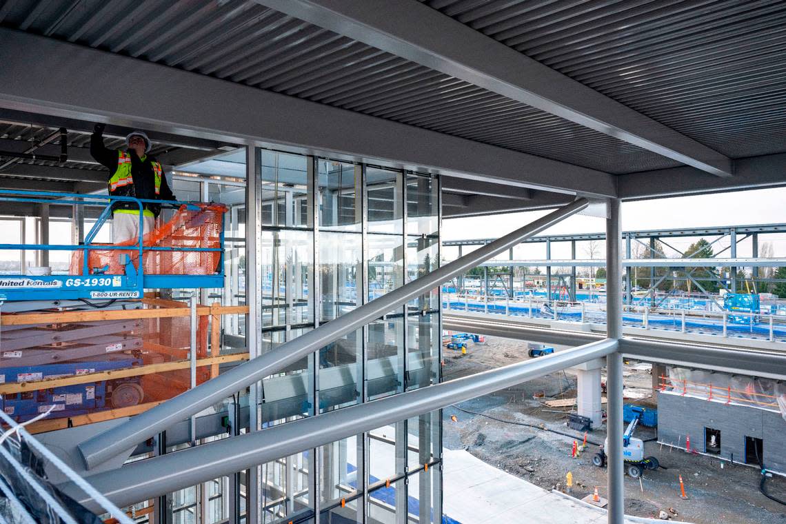 A construction worker paints a beam where the elevator will be located in the new 500-car parking garage at the Kent/Des Moines station on Wednesday, Dec. 28, 2022, in Des Moines, Wash.