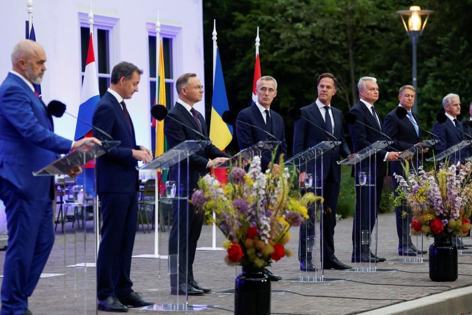 NATO leaders stand in front of podiums with their countries' flags behind them