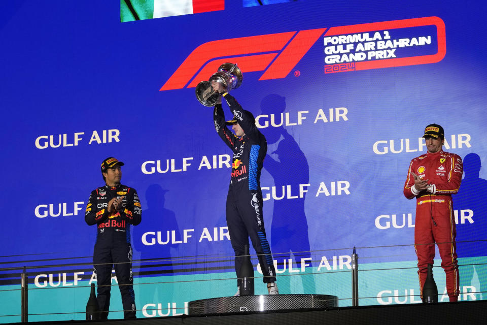 El piloto de Red Bull Max Verstappen al centro sostiene el trofeo de ganadoro del Gran Premio de Bahrein junto a Sergio Pérez, izquierda, y Carlos Sainz de Ferrari, a la derecha el sábado 2 de marzo del 2024. (AP Foto/Darko Bandic)