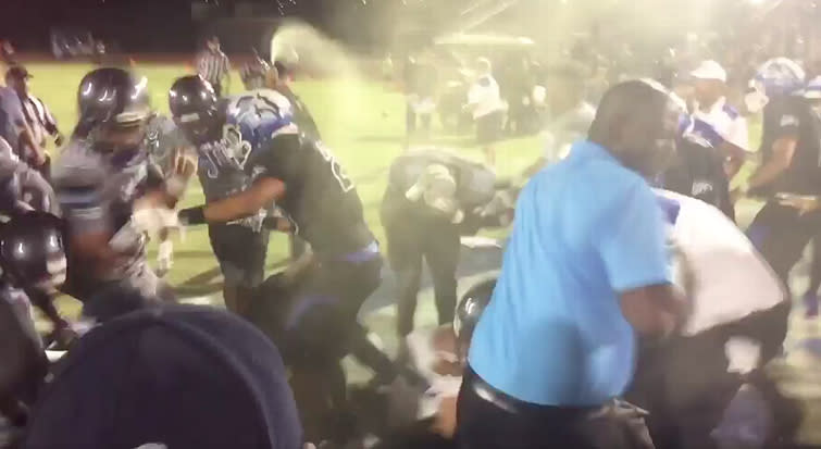 High school football players and coaches disperse after police used pepper spray to break up a brawl between the two teams. (Photo: Twitter/@JesseGranger_)