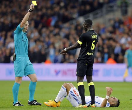 Referee Ruddy Buquet (L) gives a yellow card to FC Nantes' Remi Gomis (C) after a challenge on Olympique Marseille's Dimitri Payet (bottom) during their French Ligue 1 soccer match at the Velodrome stadium in Marseille, November 28, 2014. REUTERS/Jean-Paul Pelissier