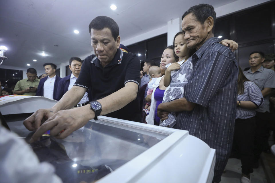 In this photo provided by the Presidential Malacanang Palace on Saturday July 20, 2019, Philippine President Rodrigo Duterte places a medal on the coffin of one of the slain police officers during his visit to their wake at Camp Lt. Col. Francisco C. Fernandez Jr. in Sibulan, Negros Oriental, in Central Philippines. On Thursday, July 25, 2019, President Rodrigo Duterte said he raised a reward of 3 million pesos ($59,000) out of anger for what he described as the Islamic State group-style killings of the officers on July 18 in Negros Oriental province. Communist guerrillas claimed responsibility for the attack but denied torturing the police officers. (Ace Morandante/Presidential Photo Via AP)