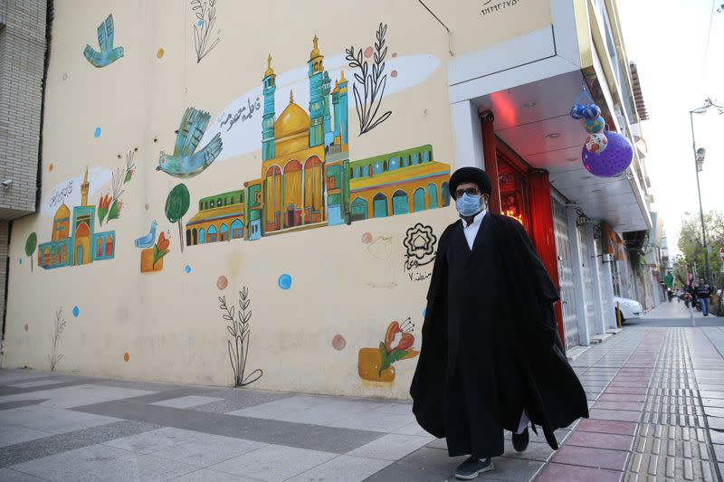 A cleric wearing a protective face mask, following the outbreak of coronavirus disease (COVID-19), walks on the street in Qom