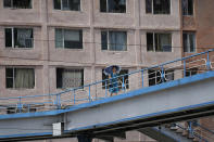 <p>A woman carrying a parasol crosses an overpass where a residential building is seen in the background on July 26, 2017, in Pyongyang, North Korea. (Photo: Wong Maye-E/AP) </p>