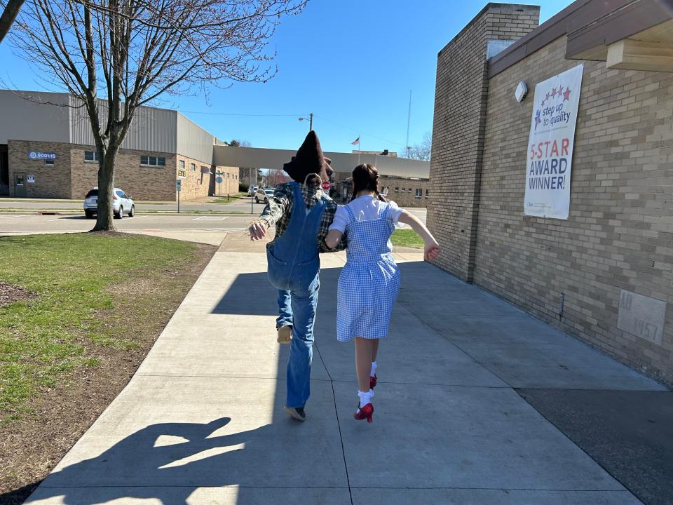 Garin Gingerich and Sydney Purcell skip down the sidewalk outside of West Elementary School as their characters, the Scarecrow and Dorothy.