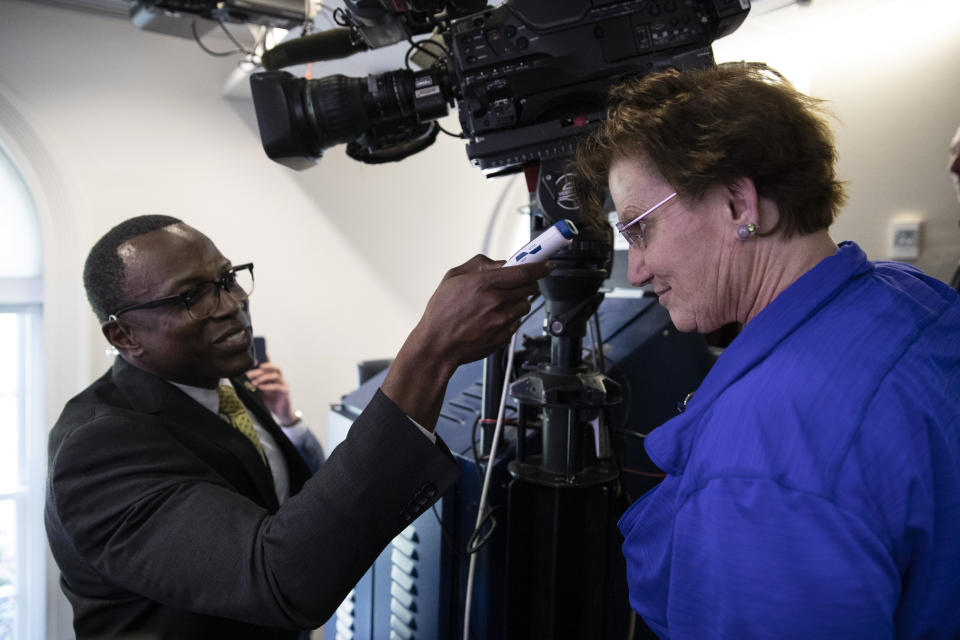 A member of the media, right, gets their temperature taken by member of the White House physicians office, over concerns about the coronavirus in the James Brady Briefing Room at the White House, Saturday, March 14, 2020, in Washington. The White House announced Saturday that it is now conducting temperature checks on anyone who is in close contact with President Donald Trump and Vice President Mike Pence. The vast majority of people recover from the new coronavirus. According to the World Health Organization, most people recover in about two to six weeks, depending on the severity of the illness.(AP Photo/Alex Brandon)